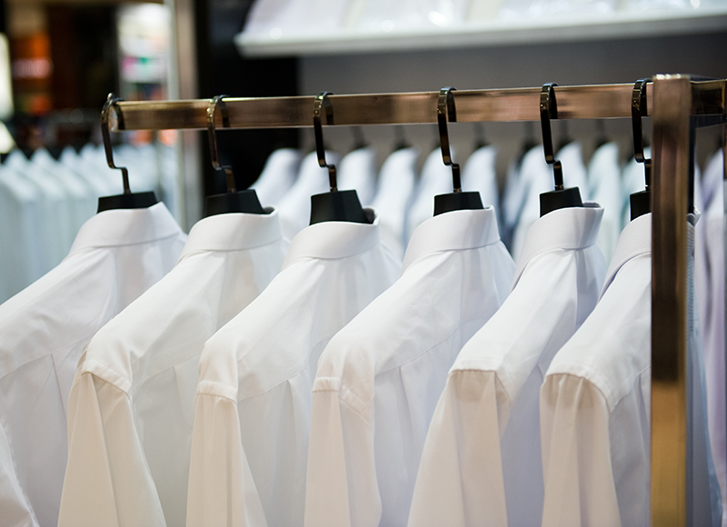 Meerdere hangers met droge gestreken witte overhemden voor hotel medewerkers.